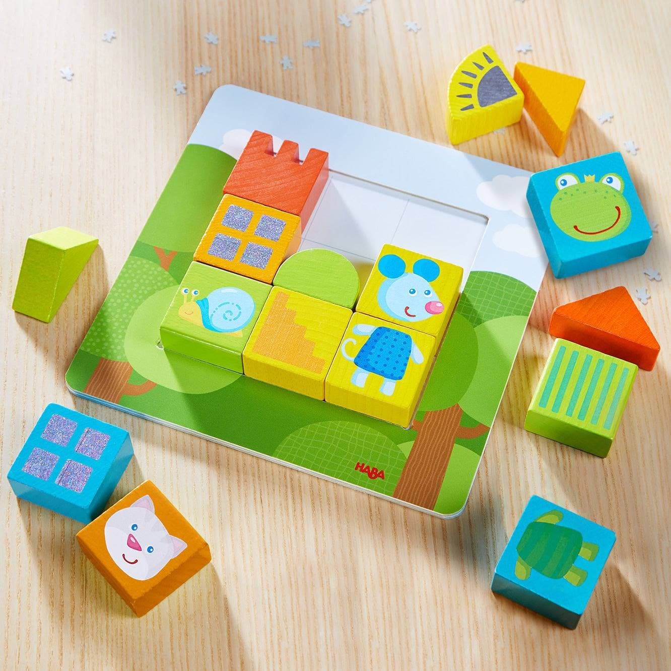 A colorful children's mechanical puzzle featuring various animal-shaped blocks on a green-themed base. The blocks include a frog, a mouse, a snail, and more, designed for arranging and engaging play. The puzzle encourages creativity and motor skills in young children.