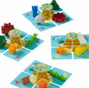 The Flotsam Float game by Haba features colorful, whimsical pieces set on playful beach-themed tiles. The game includes various wooden shapes like a tower, vehicles, and animals designed for stacking and balancing, encouraging fine motor skills and creativity in children.