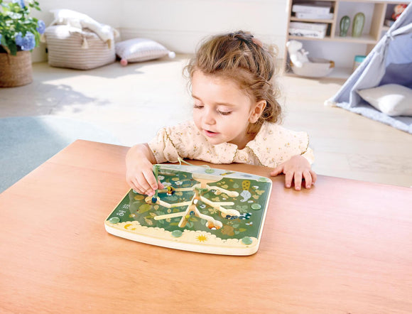 Child plays with wooden activity shaped like a tree with a stylus