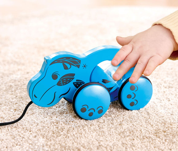 child touching blue hippo toy on carpet