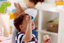 Child holding round wooden toy up to his eye