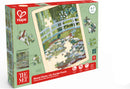 Box front of jigsaw puzzle in wooden frame depicting an illustrated bridge over a water-lily covered pond.