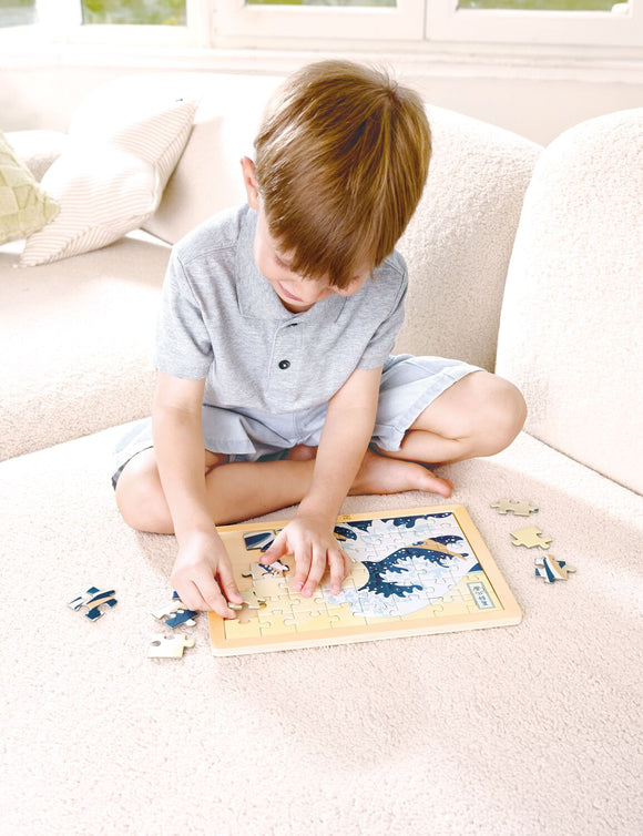 child assembling great wave puzzle on a sofa