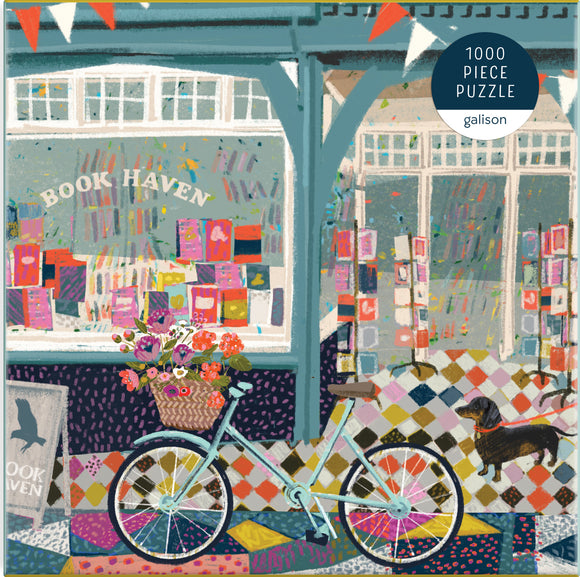 A colorful illustration of an outdoor scene featuring a quaint bookstore titled 'Book Haven.' In the foreground, a vintage bicycle with a woven basket filled with flowers is parked beside the store, which showcases an array of vibrant book covers in its windows. A small dog stands on the patterned sidewalk, completing the charming ambiance of this jigsaw puzzle titled 'Book Haven' by Galison, consisting of 1000 pieces.