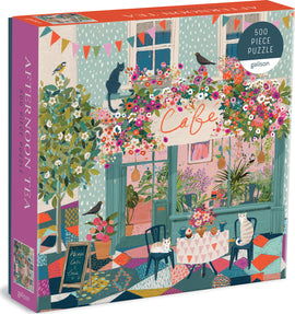 Afternoon Tea Jigsaw Puzzle by Galison featuring a colorful cafe scene with blooming flowers, playful cats, and a cozy outdoor seating area. The box displays vibrant illustrations with a charming ambiance, inviting puzzlers to unwind and enjoy assembling the 500 pieces.