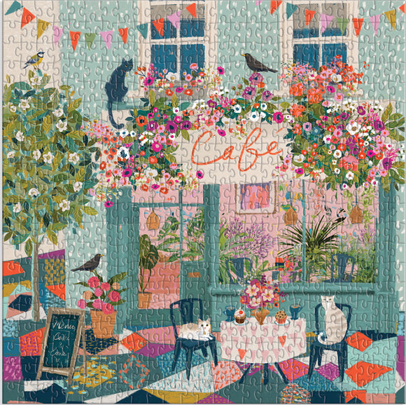 A colorful jigsaw puzzle featuring a whimsical cafe scene. The image showcases a charming outdoor cafe decorated with vibrant flowers, plants, and two cats sitting at a table with desserts. The background features cheerful bunting and an inviting atmosphere, perfect for enjoying afternoon tea.