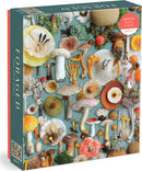 A 1000-piece jigsaw puzzle titled 'Foraged' by Galison. The puzzle features a vibrant and detailed collage of various mushrooms and foraged plants set against a soft teal background.