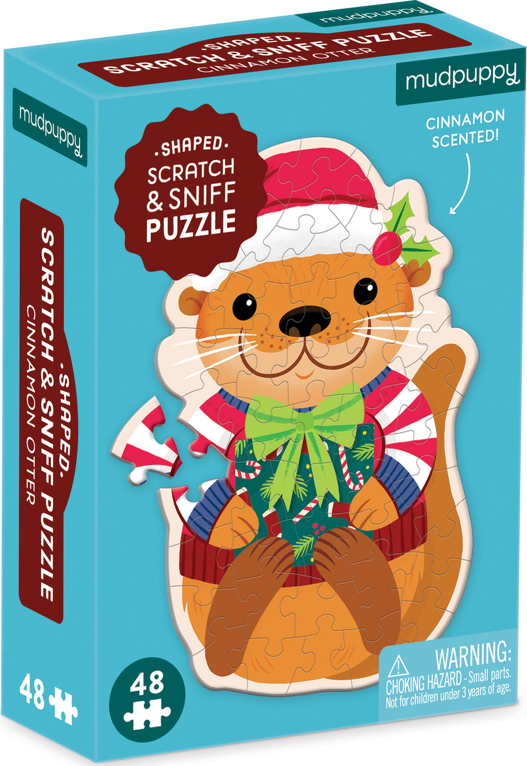 A colorful box featuring the Mudpuppy Cinnamon Otter Scratch and Sniff puzzle. The shaped jigsaw puzzle showcases a cheerful otter wearing a festive hat and holding a gift, surrounded by candy canes and holly. The box highlights that the puzzle is scented with cinnamon and contains 48 pieces.