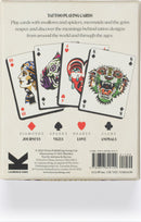 Tattoo Playing Cards featuring intricate illustrations of swallows, spiders, mermaids, and other tattoo-inspired designs. The deck includes cards for Diamonds, Spades, Hearts, and Clubs, with themes like journeys, vices, love, and animals. Each card showcases unique art reflecting the meanings behind traditional tattoo designs from around the world.