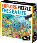 The 'Explore the Sea Life Search and Find' jigsaw puzzle by Headu features a vibrant underwater scene filled with various sea creatures, plants, and hidden objects. The colorful packaging shows fish, submarines, and an interactive flashlight component that adds to the fun of finding items within the puzzle. The recommended age is 5 and up.
