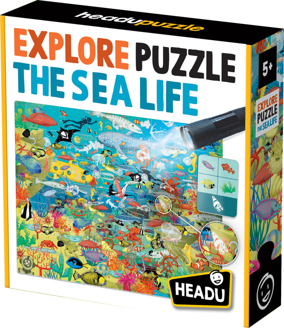 The 'Explore the Sea Life Search and Find' jigsaw puzzle by Headu features a vibrant underwater scene filled with various sea creatures, plants, and hidden objects. The colorful packaging shows fish, submarines, and an interactive flashlight component that adds to the fun of finding items within the puzzle. The recommended age is 5 and up.