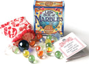 The Little Box of Marbles by House of Marbles features a vibrant packaging with colorful marbles scattered around, including a red drawstring pouch. A booklet titled 'Marbles and Games to Play With Them' is also visible. This classic game set offers entrancing fun for all ages.