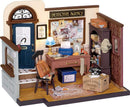 A detailed model of Mose's Detective Agency interior, featuring a blue door, a wooden desk with a typewriter and various papers, a chair with a brown backpack, a lamp, and a phone on a box labeled 'Mose's Agency.' The walls display a bulletin board covered with case files and photos, and a bookshelf filled with assorted items.