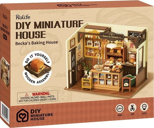 Becka's Baking House DIY miniature house kit by Robotime. The box depicts a cozy bakery complete with pastries, a display case, and a warm interior. The kit highlights wooden assembly and includes details like small bakery items and decor, suitable for ages 14 and up.