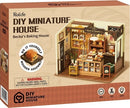Becka's Baking House DIY miniature house kit by Robotime. The box depicts a cozy bakery complete with pastries, a display case, and a warm interior. The kit highlights wooden assembly and includes details like small bakery items and decor, suitable for ages 14 and up.