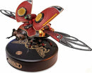 The Scout Beetle Mechanical Model by Robotime features a detailed, steampunk-inspired design with intricate mechanical components. The model showcases vibrant red and gold colors, realistic wings with a patterned design, and is mounted on a round wooden base adorned with gear motifs. Perfect for DIY enthusiasts looking to create an eye-catching display piece.