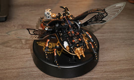 The Stag Beetle DIY kit by Robotime displayed on a wooden surface. The intricate model features metallic black and gold details, with decorative wings that resemble a beetle. It stands on a circular black base featuring a logo, showcasing its blend of art and engineering for enthusiasts and hobbyists.