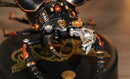 A detailed close-up of the Stag Beetle DIY model by Robotime. The model features intricate mechanical parts, including metallic claws and vibrant colors of black, orange, and gold. It is displayed on a circular base with a decorative design.