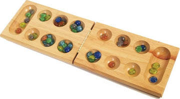 A wooden Mancala game board displayed open, featuring two rows of shallow pits filled with colorful glass marbles. The board is crafted from smooth wood with a hinge in the center for easy storage. The marbles are in various shades of green, blue, and orange, enhancing the visual appeal of this classic strategy game.