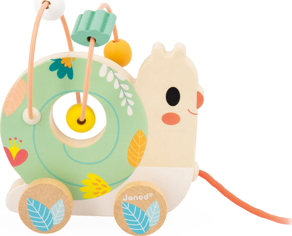 The Pure Animal Baby Looping Asst by Janod features a charming snail design with a colorful looping bead maze. It has a green spiral body decorated with floral patterns, and a smiling face. The toy includes wooden wheels and a pull string for interactive play, making it an engaging and educational toy for toddlers.