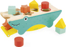 The Tropik Shape Sorting Crocodile by Janod features a playful crocodile design with multiple geometric shape cutouts. It includes colorful wooden pieces such as squares, circles, and stars, meant for sorting and placing into corresponding holes. The crocodile's vibrant colors and friendly expression make it an engaging toy for young children, encouraging cognitive development and fine motor skills.