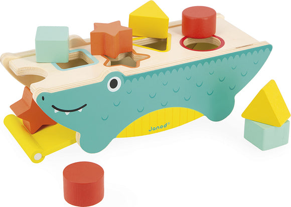 The Tropik Shape Sorting Crocodile by Janod features a playful crocodile design with multiple geometric shape cutouts. It includes colorful wooden pieces such as squares, circles, and stars, meant for sorting and placing into corresponding holes. The crocodile's vibrant colors and friendly expression make it an engaging toy for young children, encouraging cognitive development and fine motor skills.