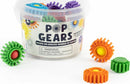 A clear container filled with colorful plastic gears in various shapes, featuring a warning label advising of small parts. Visible gears include green, yellow, blue, orange, purple, and red. The product enables children over 3 years to create endless shapes and designs, promoting creativity and fine motor skills.
