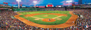 A panoramic view of Fenway Park filled with fans during a Red Sox baseball game. The vibrant green field contrasts with the packed stands under a colorful sunset sky, showcasing the excitement of the game.