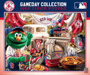 A vibrant 1000-piece jigsaw puzzle featuring the Boston Red Sox Gameday scene. The illustration includes a cheerful green mascot munching on popcorn, surrounded by baseball memorabilia like jerseys, bats, and gear, with festive tents and snacks in a lively ballpark setting.