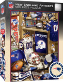 New England Patriots 500 piece jigsaw puzzle by MasterPieces. The puzzle box features an illustration of a locker filled with team memorabilia, including jerseys, helmets, footballs, and championship trophies, showcasing team pride and nostalgia for fans.