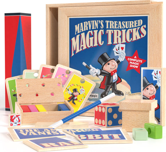 Marvin's Treasured Magic Tricks Wooden Set by Marvin's Magic displayed on a white surface. The set includes colorful cards, a wooden box with holes and colorful blocks, a wand, a red and black magic cylinder, and various other magic trick items. The top of the wooden box features an illustration of a cheerful magician. This complete magic show kit promises fun for all ages, sparking creativity and entertainment.