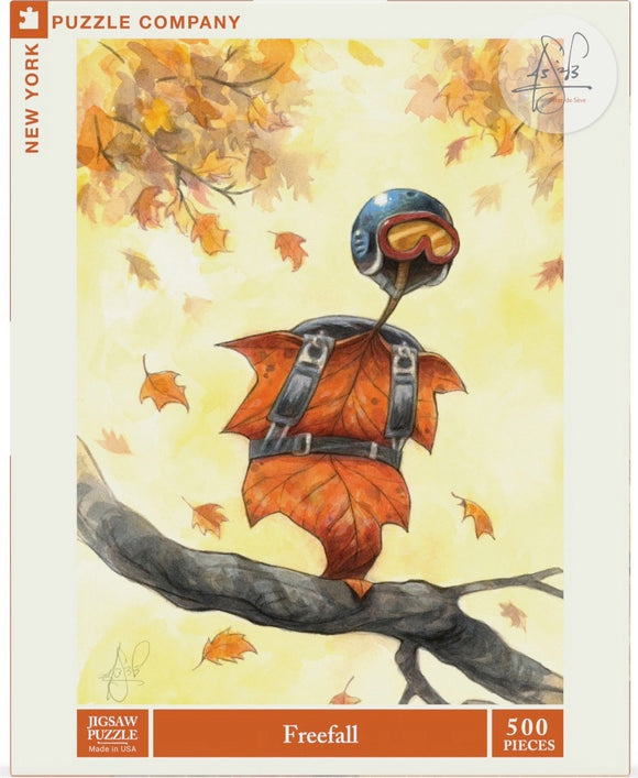 A whimsical jigsaw puzzle titled 'Freefall' by New York Puzzle Company, featuring an imaginative illustration of a leaf character wearing a helmet and goggles, ready to take flight among autumn leaves. The puzzle consists of 500 pieces and is packaged in a colorful box with a tree branch in the design.