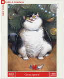 A colorful jigsaw puzzle featuring a cheerful, chubby cat sitting under a Christmas tree adorned with ornaments. The cat has large yellow eyes and a playful expression, with a small mouse toy wrapped in a red bow resting on the wooden floor in front of it. The puzzle contains 1000 pieces.