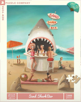 The Sand Shark Bar is a vibrant jigsaw puzzle featuring a whimsical beach scene. The illustration showcases a playful shark-themed bar with beachgoers enjoying ice cream and drinks. In the foreground, a woman relaxes on a towel, while others gather at the bar. The bright colors and fun atmosphere invite puzzle enthusiasts to dive into this 500-piece challenge.