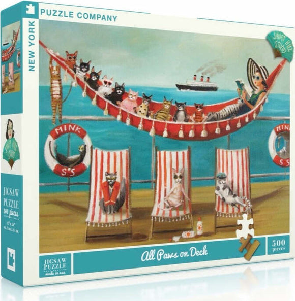The packaging of the jigsaw puzzle titled "All Paws on Deck" by New York Puzzle Company features a whimsical scene with various cats lounging on deck chairs, set against a seaside backdrop. The illustration includes a hammock filled with cats, a woman in a large hat, and nautical elements like lifebuoys and a ship in the distance. The puzzle contains 500 pieces and showcases vibrant colors and playful designs.