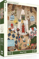 The 'Stay Cozy' jigsaw puzzle by New York Puzzle Company features a cozy indoor scene with two characters wrapped in colorful blankets, surrounded by books, textiles, and decorative items. The warm atmosphere is highlighted by soft lighting, patterned quilts, and a quaint fireplace, evoking a sense of comfort and relaxation. This 1000-piece puzzle invites you to create a delightful depiction of a snug, inviting space.