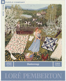 The Buttercup jigsaw puzzle by New York Puzzle Company features a charming pastoral scene with a woman holding a child, a farmer working in a field, cows grazing, and freshly laundered clothes hanging on a line. The artwork, designed by Loré Pemberton, is vibrant and colorful, showcasing a serene countryside setting with blooming flowers and a tranquil pond in the background. This 500-piece puzzle invites enthusiasts to recreate a nostalgic rural landscape.