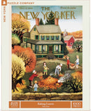A nostalgic jigsaw puzzle titled 'Raking Leaves' by New York Puzzle Company, featuring a charming autumn scene with children raking leaves near a farmhouse. The puzzle showcases vibrant colors of fall, with trees turning shades of orange and yellow, and a community spirit capturing the essence of a simpler time.