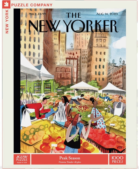 A colorful jigsaw puzzle titled 'Peak Season' by New York Puzzle Company featuring an illustration by Victoria Tentler-Krylov. The design showcases a vibrant farmers' market scene with people engaging in transactions, surrounded by a variety of fresh fruits and vegetables, set against a backdrop of city buildings.