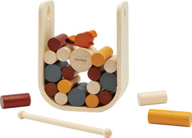 Beaver Tumble by Plan Toys is a mechanical puzzle featuring a wooden structure with colorful cylindrical pieces. A playful beaver figure sits atop the stacked pieces, encouraging creative play and problem-solving. The set includes various wooden rods and cylinders in different colors, designed to enhance fine motor skills and spatial awareness in children.