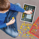 A child sitting on the floor, intently playing with the Peg Code Peg and Letters in Co game. They hold a yellow letter piece while engaging with a board displaying various letters and symbols. Colorful pegs scattered around enhance the playful atmosphere.
