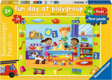 The Ravensburger MFP Fun Day at Playgroup jigsaw puzzle features a colorful illustration of children playing and learning in a playgroup setting. It shows a boy and girl engaged in activities at a table filled with toys and books, surrounded by various play items like blocks, a fire truck, and a toy dog. The vibrant scene is designed for young children, promoting fun and education through a 16-piece puzzle suitable for ages 2 and up.