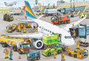 A colorful illustration of a busy airport scene featuring a large airplane being serviced. Ground vehicles such as fuel trucks, luggage carts, and maintenance vehicles surround the plane. Airport staff in safety gear are actively working on the tarmac, loading luggage, and preparing for aircraft departure. Various airplanes are visible in the background, with a control tower overseeing the bustling activity.