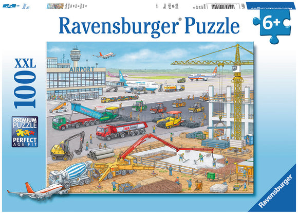 A colorful jigsaw puzzle titled 'Construction at the Airport' by Ravensburger. The image features a busy airport scene with various construction vehicles, workers in safety gear, airplanes on the runway, and an airport terminal in the background. It highlights the hustle and bustle of construction activity, showcasing trucks, cranes, and machinery working together. Designed for ages 6 and up.