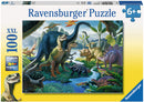 A colorful jigsaw puzzle featuring a vibrant prehistoric scene with various dinosaurs and lush greenery. The puzzle consists of 100 pieces and is suitable for ages 6 and up, made by Ravensburger. The packaging displays images of the dinosaurs and jungle environment.