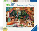 A Ravensburger 500-piece jigsaw puzzle titled 'Cozy Glamping' featuring a beautifully designed rustic interior with a bathtub, chandelier, and fireplace. Surrounding the cozy space are elements of nature visible through large windows, including a serene outdoor scene with a stream and greenery. The puzzle is in a large format, ideal for easy handling, and showcases a warm, inviting atmosphere with decorative items like flowers and snacks.