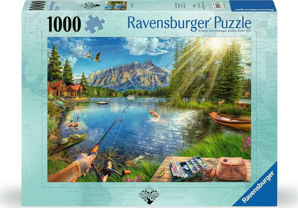 Ravensburger jigsaw puzzle titled 'Life at the Lake' featuring a serene lakeside scene. The image depicts a tranquil lake surrounded by lush trees, a few fishing boats, and cabins. A person is seen fishing, and ducks are swimming in the water under a bright blue sky with fluffy clouds.