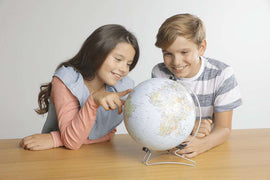 The Earth 3D 540 piece jigsaw puzzle by Ravensburger displayed with a globe and two children engaging in exploration. One child points at a location on the globe while the other smiles, highlighting the educational and fun aspect of this puzzle.