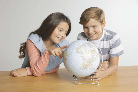 The Earth 3D 540 piece jigsaw puzzle by Ravensburger displayed with a globe and two children engaging in exploration. One child points at a location on the globe while the other smiles, highlighting the educational and fun aspect of this puzzle.