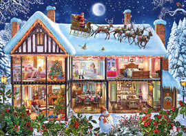 A vibrant jigsaw puzzle design titled 'Christmas at Home Seasonal 100' by Ravensburger. It depicts a cozy house decorated for Christmas, showcasing a snow-covered roof, Santa in his sleigh, and various festive scenes inside each room including a decorated tree, a family gathering, and a snowman outside.